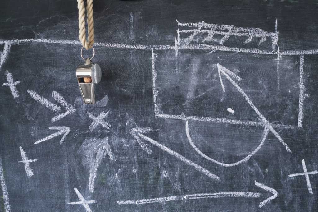 Tactical diagram of soccer plays in white chalk on a blackboard.